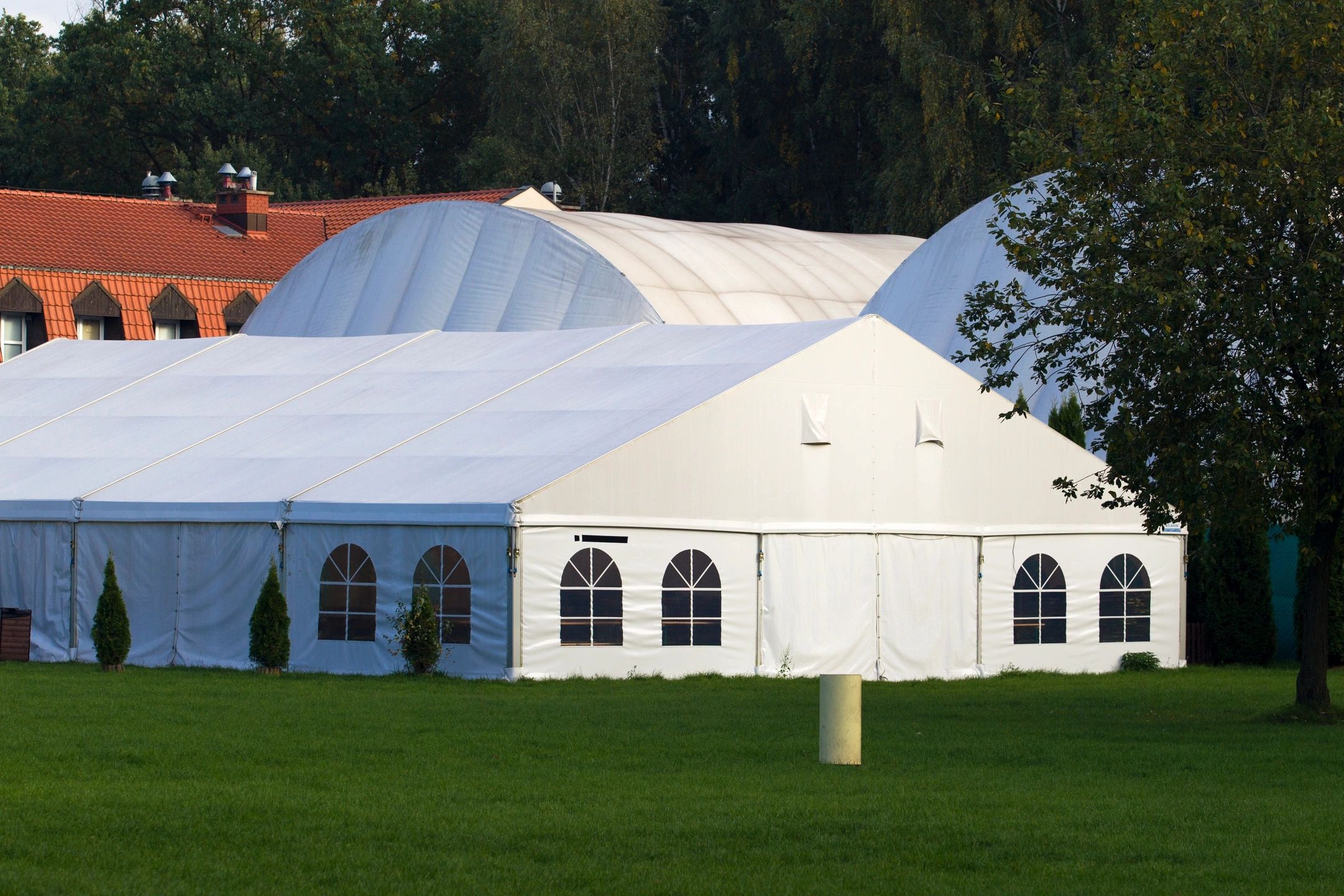 Large white and blue event tent on manicured lawn