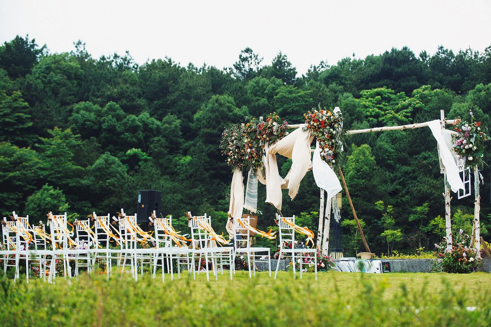 Outdoor wedding ceremony with wooden arbor and white chairs